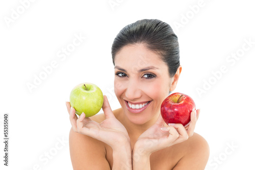 Happy brunette holding red and green apples and looking at camer