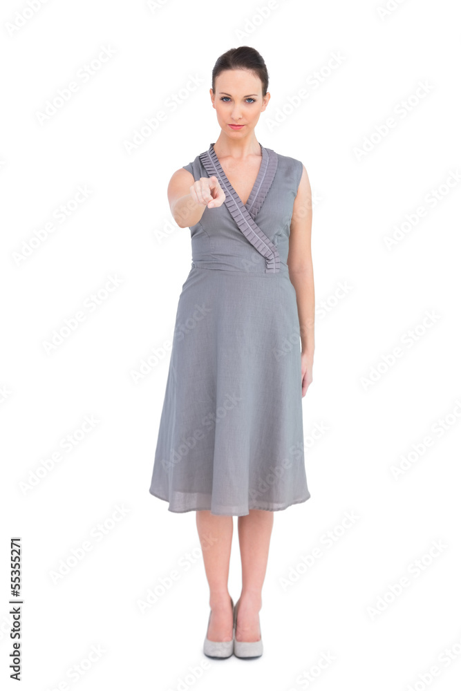 Serious elegant brunette in classy dress pointing at camera Serious elegant brunette in classy dress pointing at camera