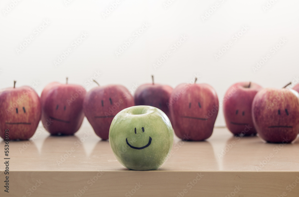 Green and happy apple among red and sad apples