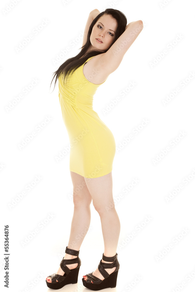 Woman yellow short dress stand hands behind head Woman yellow short dress stand hands behind head