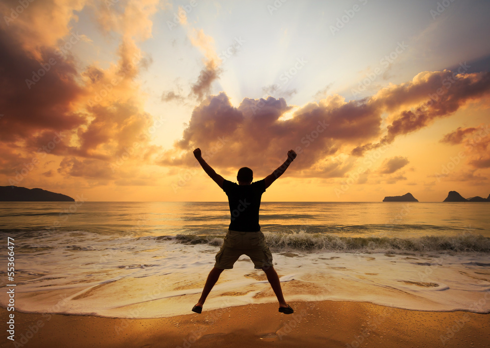 Happy man jumping over sea. Sand beach at dawn.