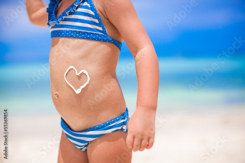 Close-up heart painted by sun cream on little girl stomach