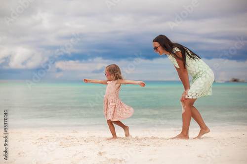 Little girl with her mother dancing at white sandy beach on a