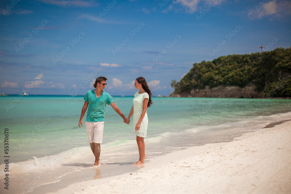 Young couple walking on sandy beach near the sea