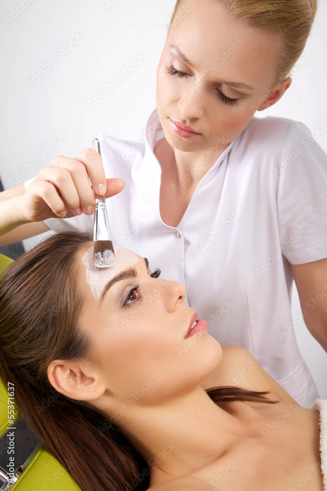 Fototapeta premium young woman getting beauty skin mask treatment on her face with