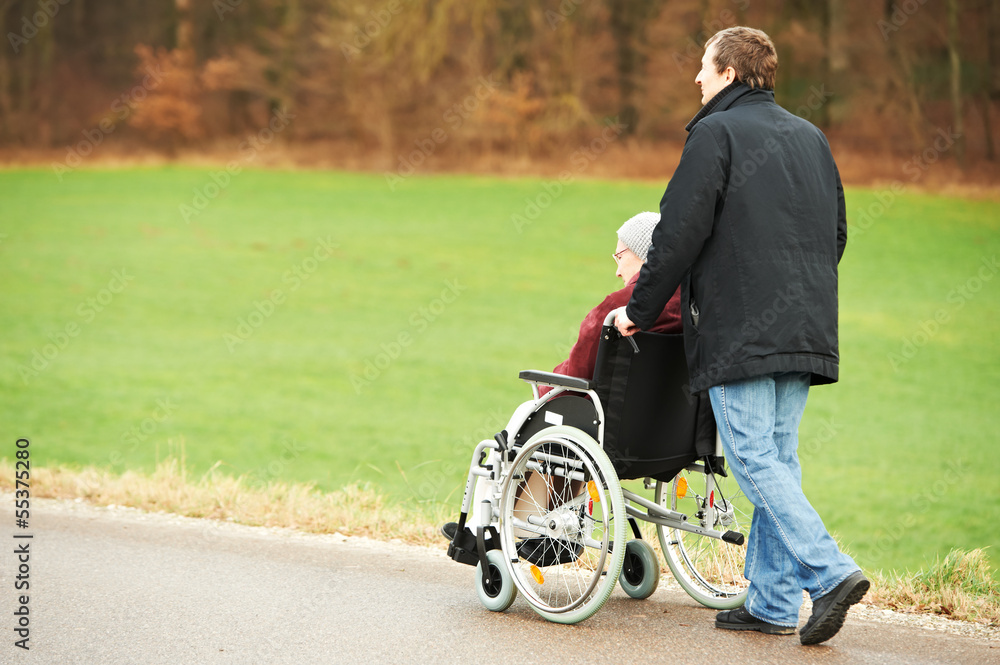 old senior woman in wheelchair with careful son old senior woman in wheelchair with careful son