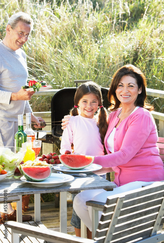 Grandparents And Granddaughter Having Outdoor Barbeque