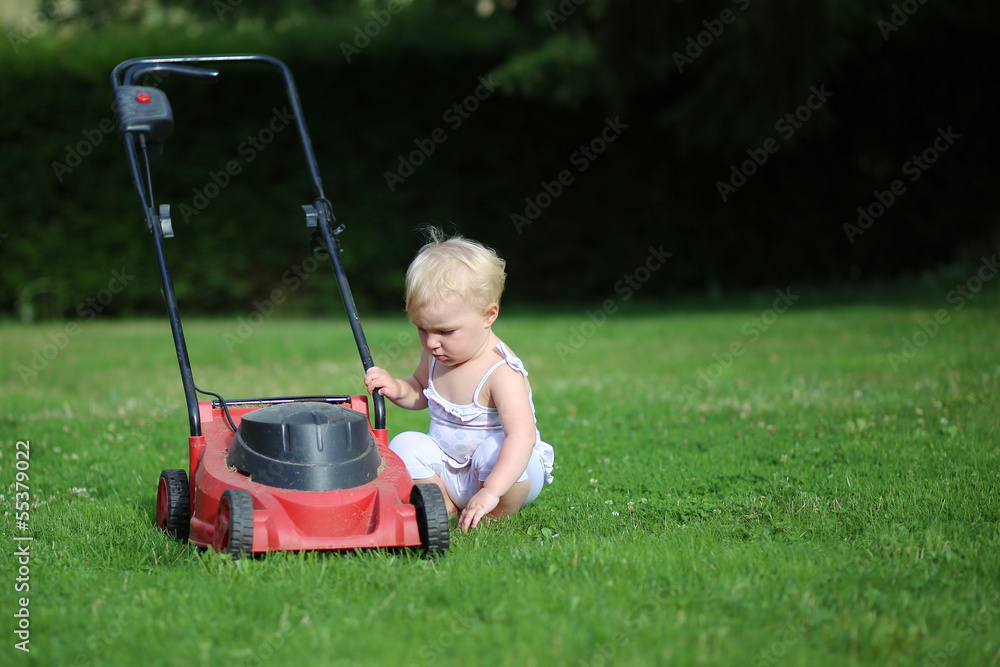 Funny little baby girl is playing outside with lawn machine Funny little baby girl is playing outside with lawn machine