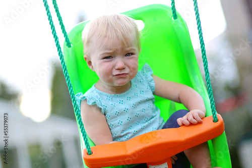 Lovely upset baby swinging at playground