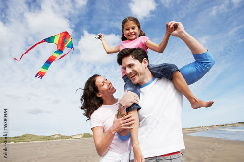Family Having Fun Flying Kite On Beach Holiday