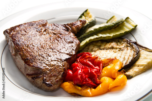 Delicious beef steaks on white dish with grilled vegetables