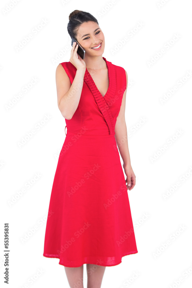 Smiling elegant brunette in red dress on the phone posing Smiling elegant brunette in red dress on the phone posing