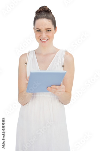 Happy young model in white dress holding tablet computer