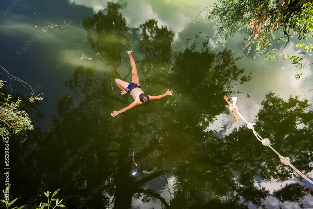 A boy jumps in a lake with a bungee jumping