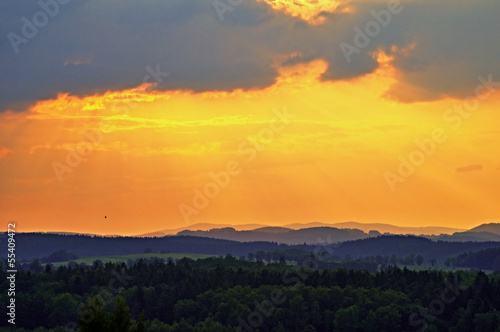 The sky at sunset over forests and forested mountains