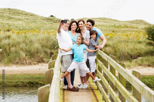 Multi Generation Family Walking On Bridge Taking Photo photo