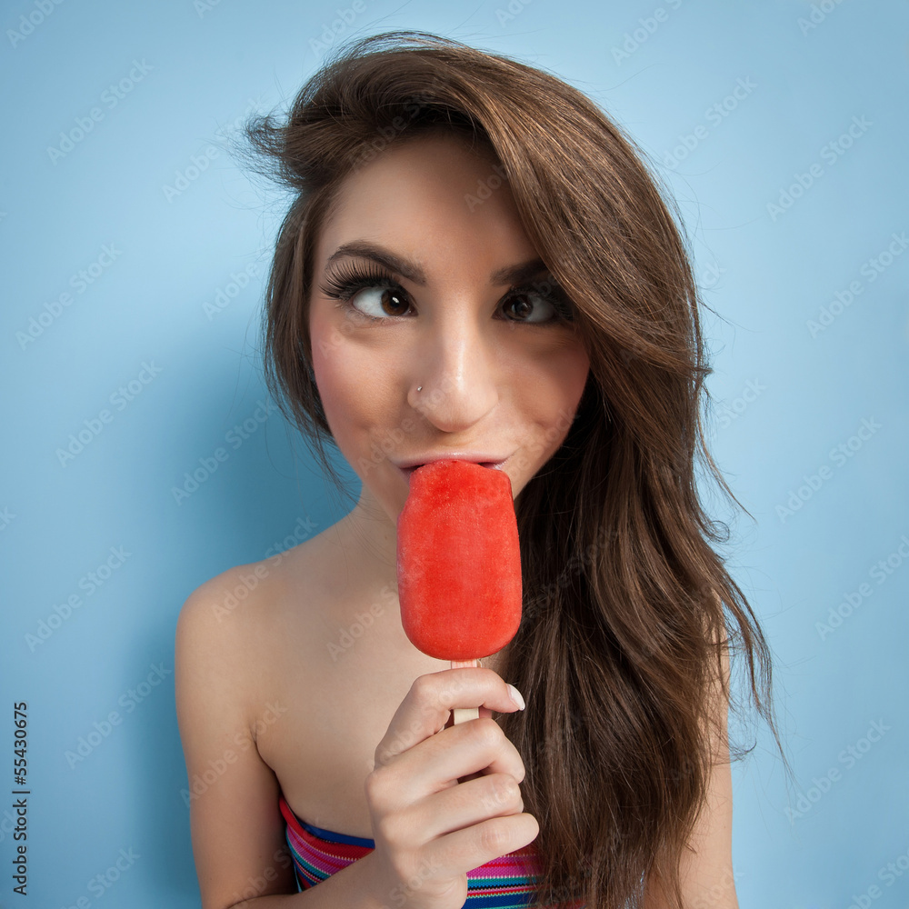 Crossed eyes girl eating ice cream against blue background. Crossed eyes girl eating ice cream against blue background.