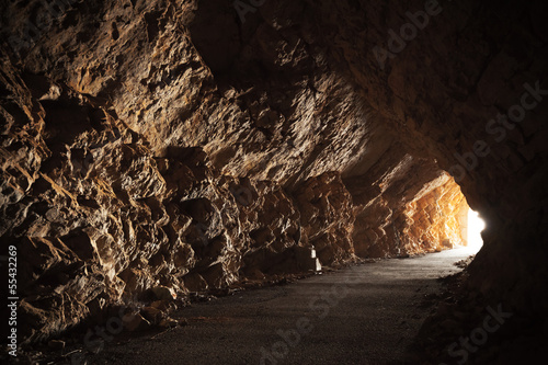 Fototapeta Empty road goes through the cave with glowing end
