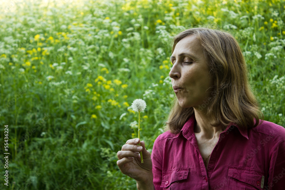 Woman blowing on a dandelion Woman blowing on a dandelion