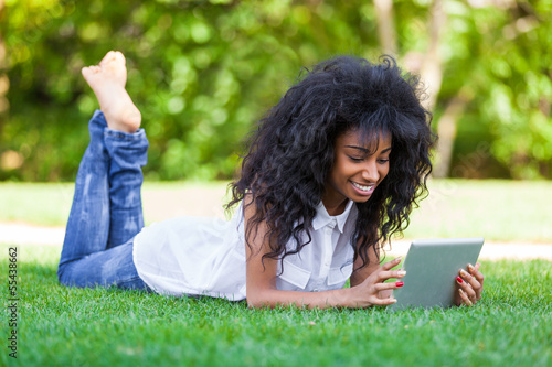 Outdoor portrait of a teenage black girl using a tactile tablet