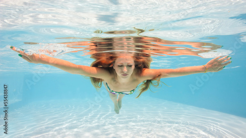 Underwater woman portrait wearing bikini in swimming pool.