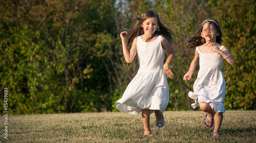 Young sisters running together in the park.