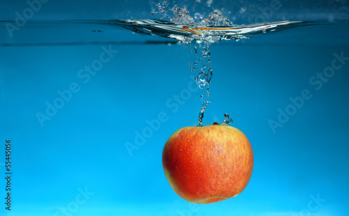 Yellow apple in the water splash over blue