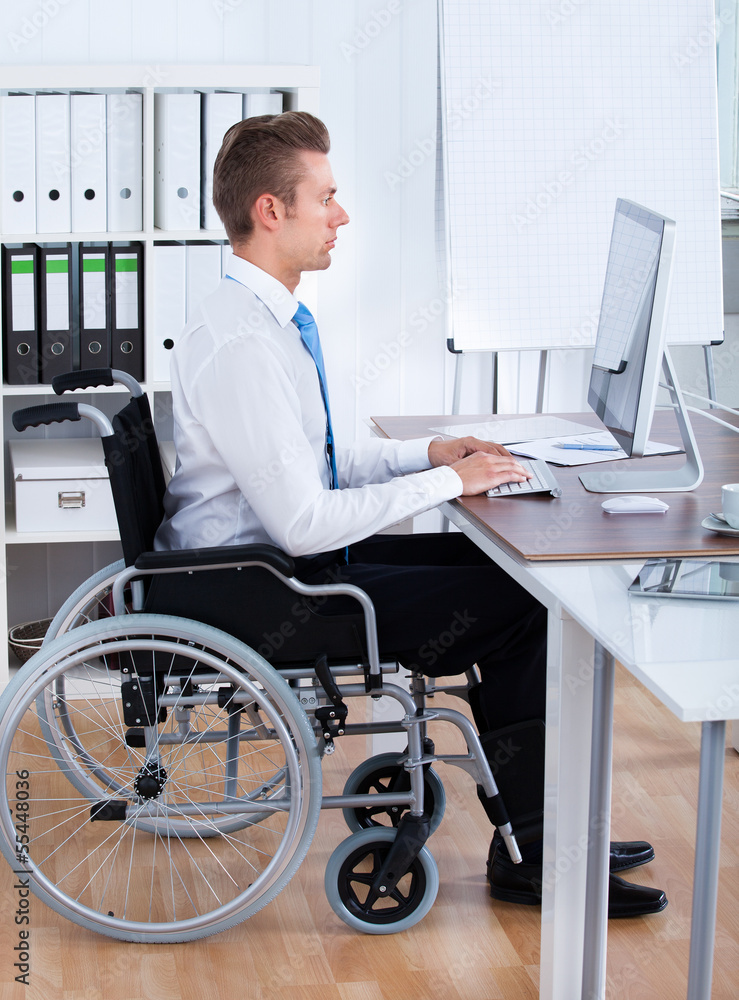 Businessman Sitting On Wheelchair And Using Computer Businessman Sitting On Wheelchair And Using Computer
