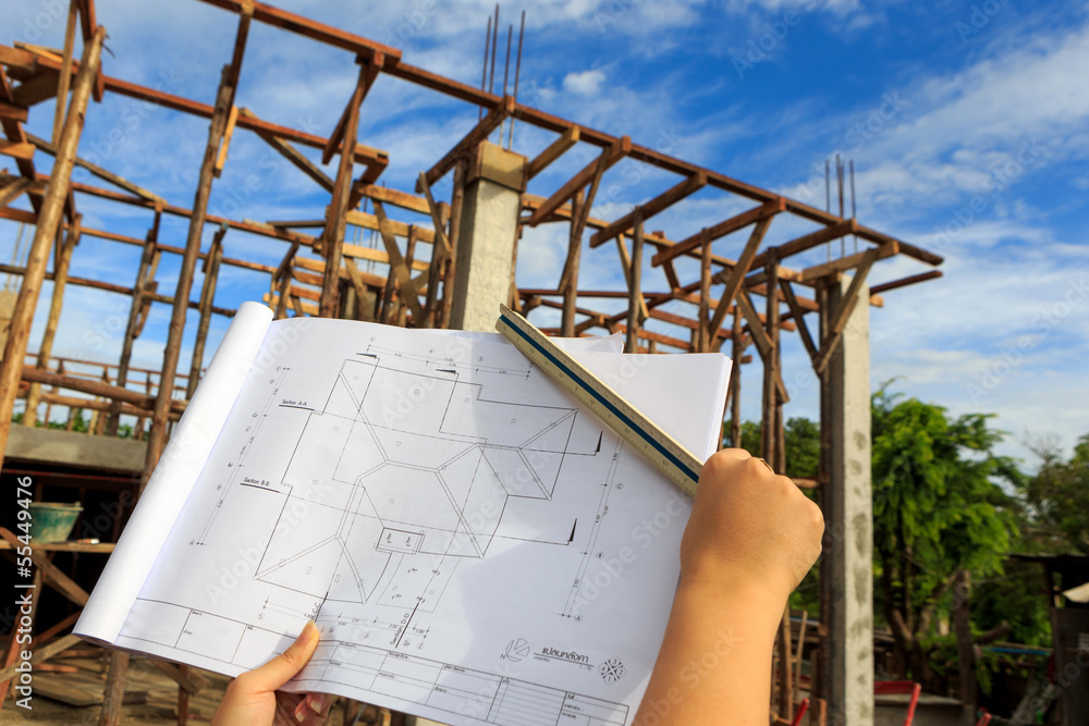architecture drawings in hand on house building background with
