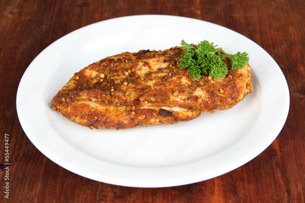 Roasted chicken fillets on white plate, on wooden background