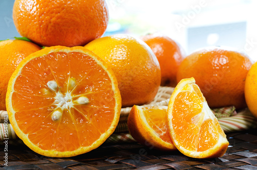 tangerines with leaves in a beautiful basket  on wickerwork tabl