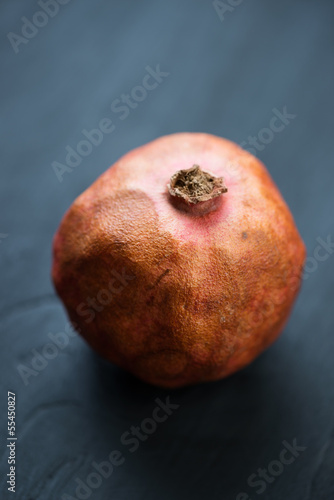 Ripe pomegranate over dark wooden background, vertical shot