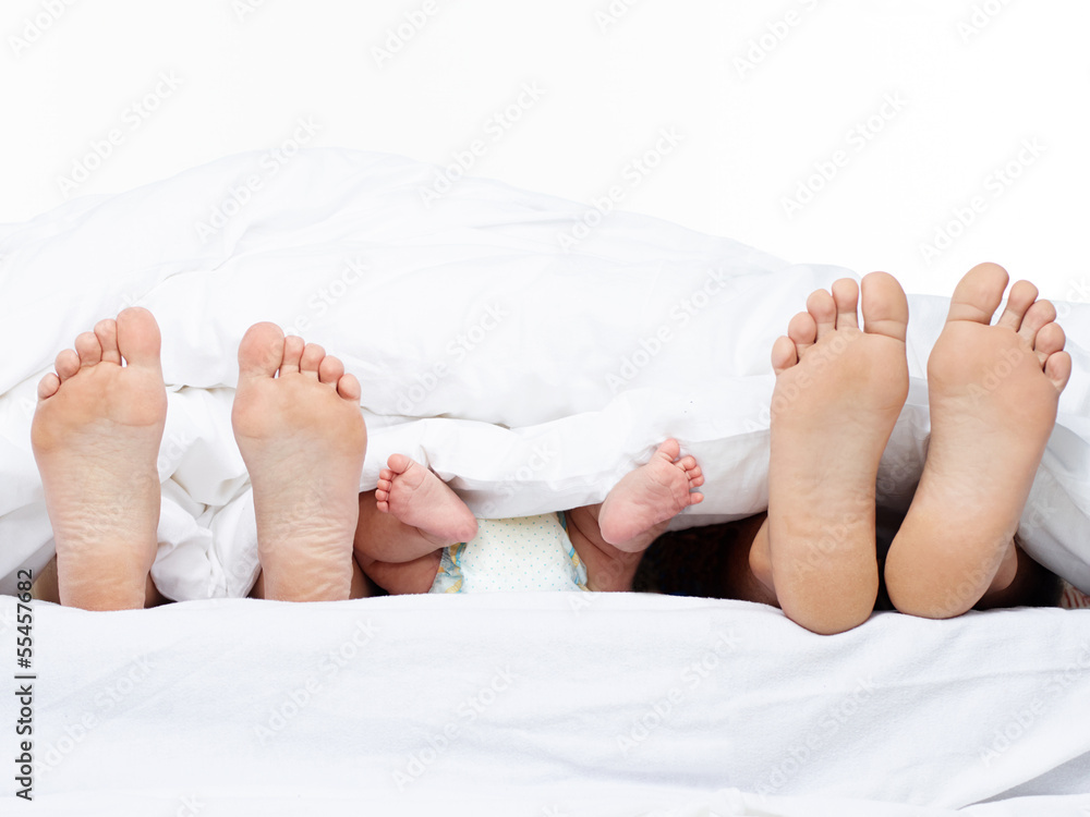 Feet of a family sticking out from the quilt Feet of a family sticking out from the quilt