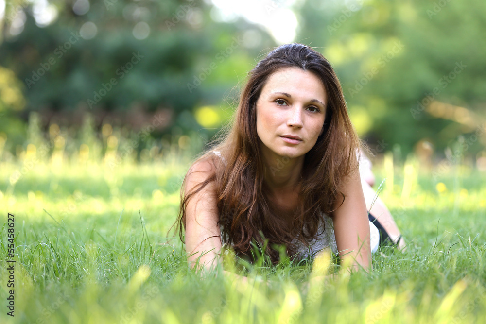 young brunette beautiful girl lying on meadow. outdoor portrait. young brunette beautiful girl lying on meadow. outdoor portrait.