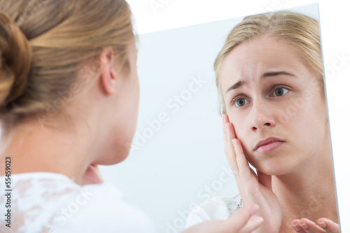 Teen girl unhappy with their appearance in mirror