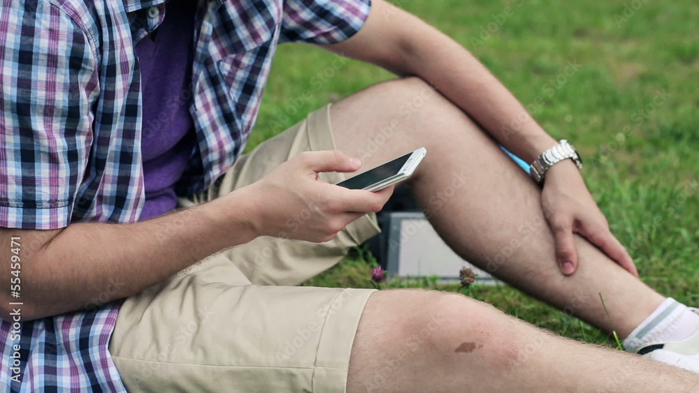 Man sending sms, texting on smartphone in the park Man sending sms, texting on smartphone in the park
