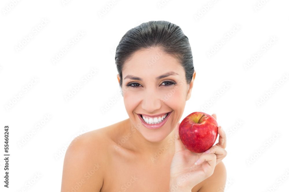 Happy brunette holding a red apple and looking at camera Happy brunette holding a red apple and looking at camera