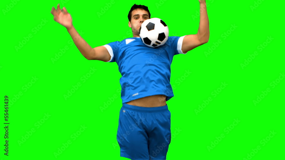 Handsome man controlling a football with his chest on green Handsome man controlling a football with his chest on green