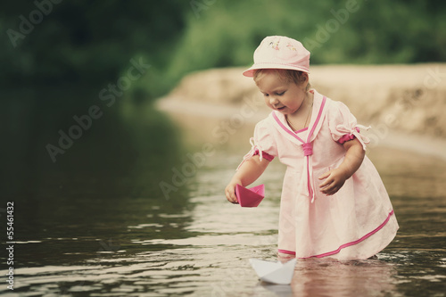 Fototapeta Naklejka Na Ścianę i Meble -  little girl plays with paper boats in river