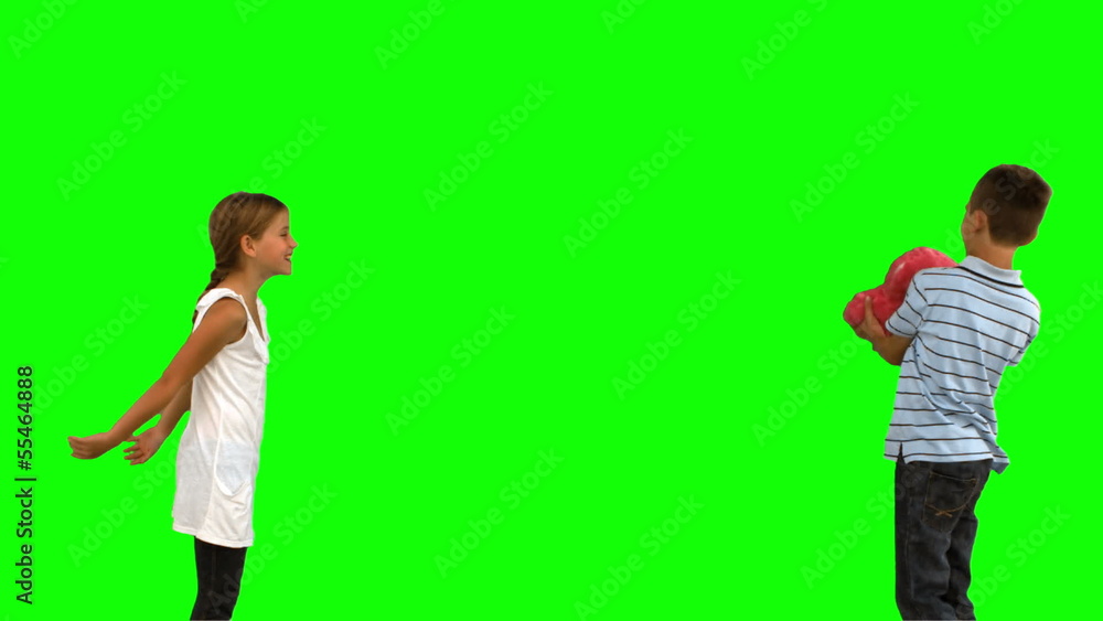 Siblings playing with a heart shaped cushion on green screen Siblings playing with a heart shaped cushion on green screen