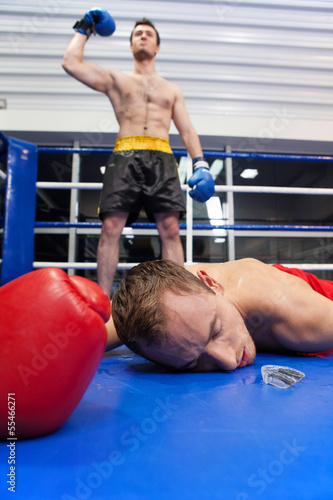 Winner and loser. Confident young boxer keeping his arm raised w photo