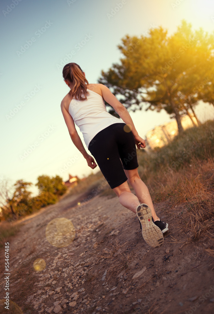 Fototapeta Jogger woman running outdoors. Young female exercising.