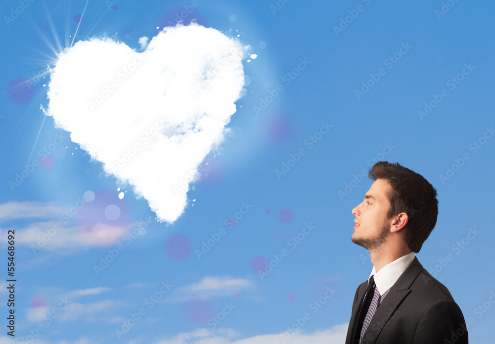 Handsome man looking at white heart cloud on blue sky Handsome man looking at white heart cloud on blue sky