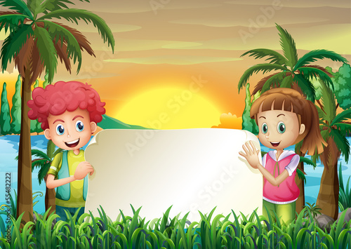 A young man and woman holding an empty signage at the riverbank