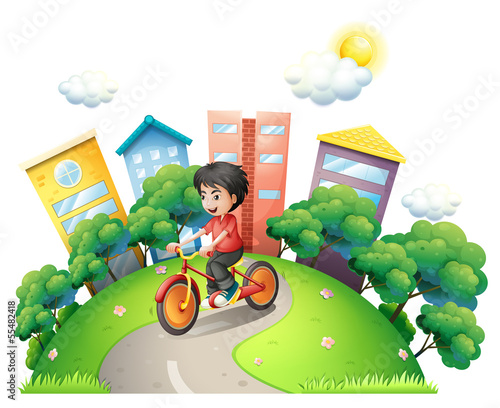 A boy biking at the road going to the high buildings