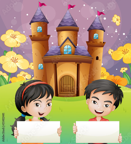 Two kids with empty signages standing in front of the castle