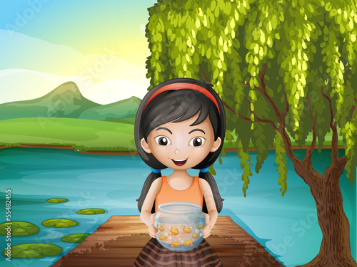 A girl with an aquarium standing at the riverbank