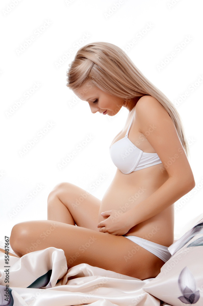 The pregnant woman sits isolated on white The pregnant woman sits isolated on white