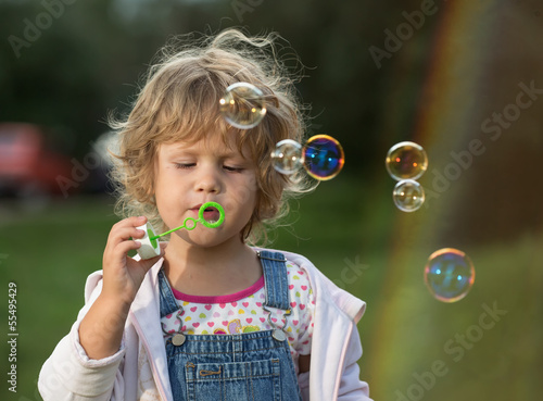 The little girl inflates soap bubbles