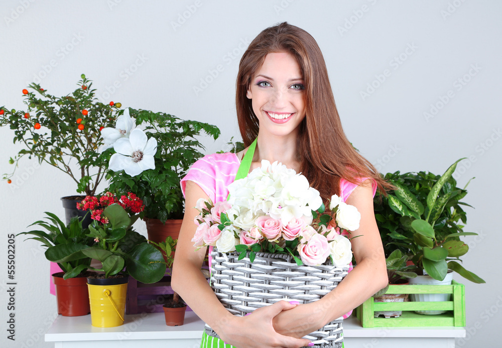 Beautiful girl gardener with flowers on grey background